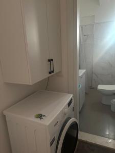 een witte badkamer met een wasmachine en een toilet bij Vlora Central & Comfy Apartment in Vlorë