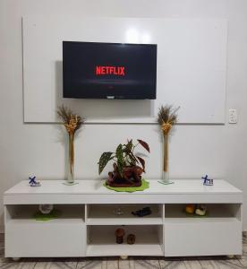 uma prateleira branca com vasos e uma televisão na parede em Casa Groot em Holambra