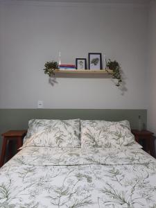 Una cama con un edredón con dos cuadros encima. en Casa Groot, en Holambra