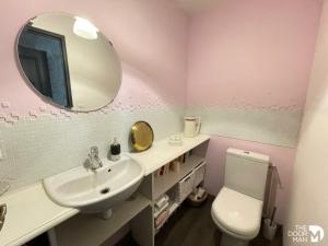 uma casa de banho com um lavatório, um espelho e um WC. em Au moulin de Pascaline 