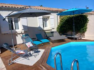 een zwembad met stoelen en parasols naast een huis bij Villa Les oliviers in Le Pontet