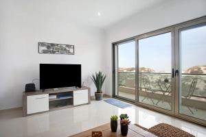 a living room with a flat screen tv and large windows at Azul Aprumado in Peniche de Cima