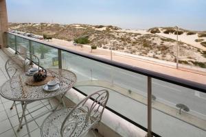 a balcony with a table and chairs and a view of the beach at Azul Aprumado in Peniche de Cima