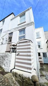 un edificio blanco con una puerta delante en AMAZING LOCATION - "SMUGGLERS HIDE" & "SMUGGLERS CABIN" - a 2 BEDROOM FISHERMANS COTTAGE with HARBOUR VIEW and also a private entrance 1 BED STUDIO - 10 Metres To Sea Front - BOOK BOTH for ENTIRE 3 BEDROOM COTTAGE - 2023 GLOBAL REFURBISHMENT AWARD WINNER en St Ives