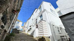 a white building on the side of a street at SMUGGLERS HIDE COTTAGE and separate but connecting SMUGGLERS CABIN - - In a beautifully renovated fishermans cottage - - HARBOUR VIEWS - - BEACH only 10 metres - - RENOVATION AWARDS WINNER - - Book Both For An Even Larger Property in St Ives