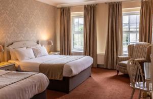 une chambre d'hôtel avec deux lits et une chaise dans l'établissement Kee's Hotel, à Stranorlar