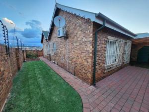 a brick building with a patio and green grass at Nkulies Nest in Centurion