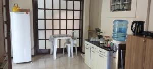 a kitchen with a refrigerator and two white stools at Hostel de gaia in Santa Cruz do Sul