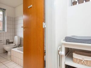 a bathroom with a toilet and a wooden door at Family-Friendly House by the Beach in Ebeltoft +28 photos
