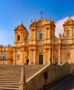 Un grand bâtiment avec des escaliers se trouve juste devant. dans l'établissement Love Noto, à Noto
