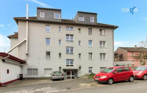 un gran edificio blanco con coches aparcados en un aparcamiento en BEGE APARTMENTS WorkAway Residence, en Bochum