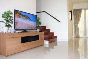 uma sala de estar com uma televisão de ecrã plano num centro de entretenimento em madeira em Lovely Townhouse in Laguna Park em Thalang
