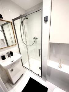 a white bathroom with a shower and a sink at Przytulna Kawalerka z obiadem w cenie in Bielsko-Biała