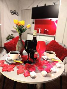 stół z dwoma kubkami i kieliszkami do wina i kwiatami w obiekcie Hortensja 309 w Koszalinie