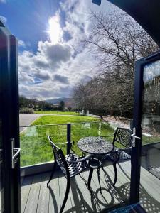 una mesa y sillas sentadas en un porche con ventana en Tanglewood Loft en Newry