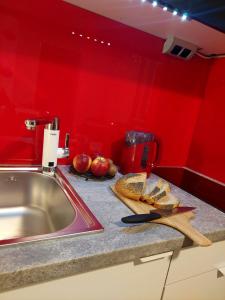 a red kitchen with a counter with bread and a knife at Hortensja 309 in Koszalin