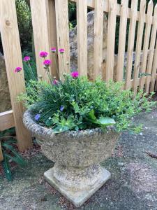 a stone planter with flowers in it next to a fence at Cosy retreat in the heart of the Cotswolds. in Chipping Norton