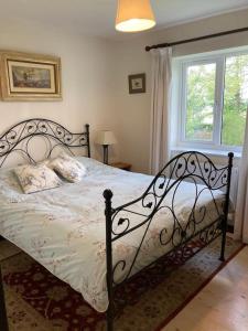 a bedroom with a bed with a black frame and a window at Cosy retreat in the heart of the Cotswolds. in Chipping Norton
