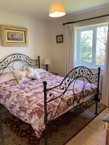 a bedroom with a bed with a pink comforter and a window at Cosy retreat in the heart of the Cotswolds. in Chipping Norton