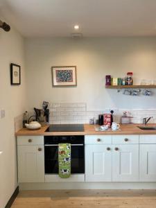 a kitchen with white cabinets and a stove top oven at Cosy retreat in the heart of the Cotswolds. in Chipping Norton