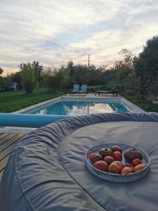 a bowl of fruit on a table next to a swimming pool at La bulle des champs in Champmotteux