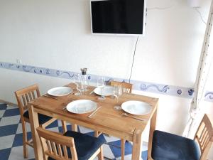 a wooden table with plates and wine glasses on it at Casa Marina - Le Petit Bleu Vue mer in Pornic