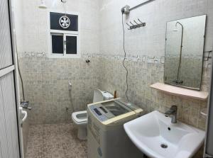 y baño con lavabo, aseo y espejo. en Al Manafa Furnished Apartments, en Salalah