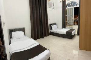 a hotel room with two beds and a window at Al Manafa Furnished Apartments in Salalah