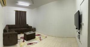 a living room with a couch and a tv at Al Manafa Furnished Apartments in Salalah
