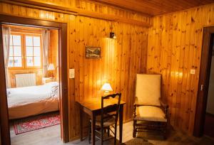 ein Schlafzimmer mit einem Bett und einem Schreibtisch mit einem Stuhl in der Unterkunft Hôtel-Restaurant Le Berger Blancc in Evolène