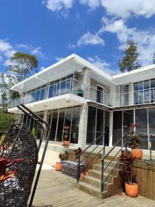 a white house with glass windows and stairs at Hermosa habitación 203 deluxe GC in Guatapé
