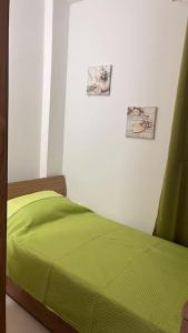 ein Schlafzimmer mit einem grünen Bett mit zwei Bildern an der Wand in der Unterkunft Marsaxlokk 3 Bedroom Penthouse in Marsaxlokk