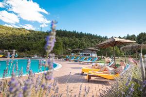 a group of people sitting in chairs by a pool at ECO HOTEL ORLANDO Sardegna in Villagrande Strisaili