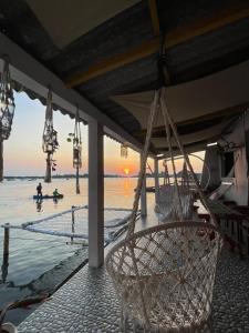 eine Hängematte am Strand mit Sonnenuntergang im Hintergrund in der Unterkunft Loyal friend hostel karimunjawa in Karimunjawa