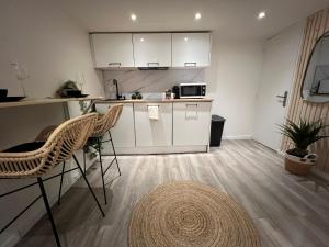 a kitchen with white cabinets and chairs and a table at Le zénith vieille ville d'Annecy in Annecy