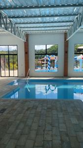 a large swimming pool with blue water and windows at Hotel Campestre Atibaia in Atibaia