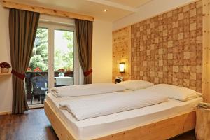 1 dormitorio con 1 cama grande y pared de ladrillo en Hotel Olympia en Sarntal