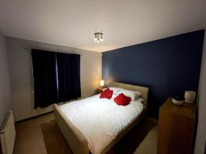 a bedroom with a bed with red pillows on it at Aberdeen Beach 2 Bed Apartment in Aberdeen