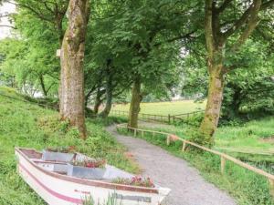 a boat sitting on a path next to trees at Bwthyn Derrick in Tal-gareg