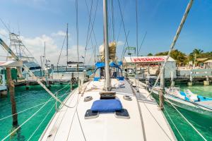 a sailboat docked at a dock in the water at Walk barefoot to beach! Private Sailboat at North End, queen bed, en-suite bath, AC in Isla Mujeres