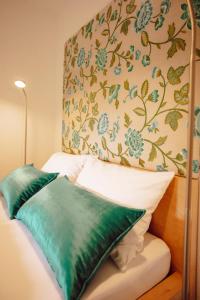 uma cama com almofadas verdes e uma parede floral em it‘s me em Wernigerode