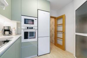 a kitchen with white cabinets and appliances and a door at Playa y descanso con parking by CABANA Rentals in Ribeira