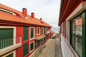 an alley between two buildings with red and green shutters at Playa y descanso con parking by CABANA Rentals in Ribeira
