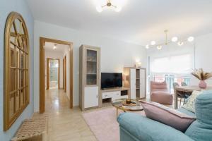 a living room with a blue couch and a tv at Playa y descanso con parking by CABANA Rentals in Ribeira