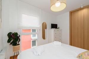 a bedroom with a white bed and a window at Playa y descanso con parking by CABANA Rentals in Ribeira