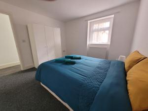 a bedroom with a blue bed and a window at Lovely 2-Bed fully refurbished House in London in London