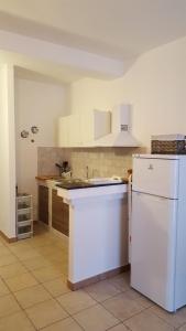 uma cozinha com armários brancos e um frigorífico branco em VELA BIANCA em Punta Braccetto