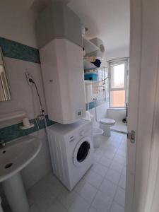 uma casa de banho com uma máquina de lavar roupa e um lavatório em VELA BIANCA em Punta Braccetto