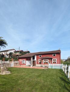 a red house with a white fence in a yard at Casa de campo La Casuca Del Monje in La Acebosa