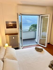 ein Schlafzimmer mit einem weißen Bett und einem großen Fenster in der Unterkunft Buddy'S House in Abbadia Lariana